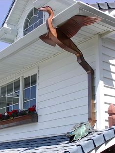 a bird statue on the roof of a house