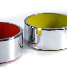 two metal containers with red, yellow and green lids on white table top next to each other