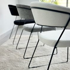 four chairs are lined up in a row on the carpeted floor, one is black and white