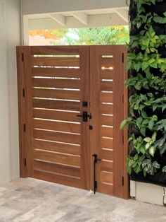 an open wooden door in front of a green wall with plants growing on the side