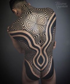 a man with tattoos on his back is holding onto an intricate piece of art that appears to be in the shape of a human body