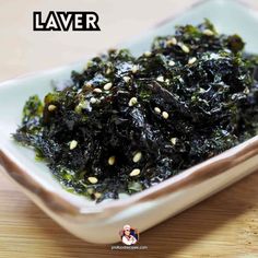 a white bowl filled with seaweed on top of a wooden table