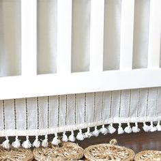 several pieces of rope sit on the floor in front of a white crib with tassels hanging from it