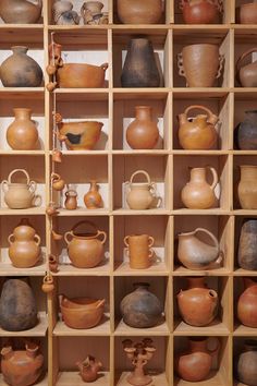 a shelf filled with lots of vases and pots on top of wooden shelves next to each other