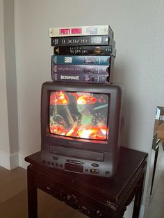 a tv sitting on top of a wooden table next to a stack of dvd's