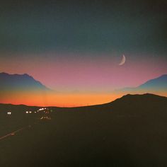 the sun is setting over some mountains with cars going down one side and a half moon in the distance