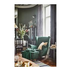 a living room filled with furniture and a green chair in front of a large window