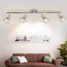 a living room with a brown couch and three lights on the ceiling over it's head