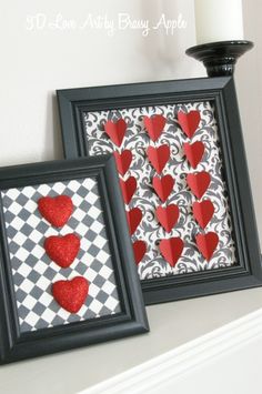 two framed pictures with red hearts on them next to a white candle and black vase