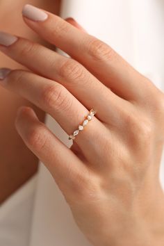 a woman's hand wearing a gold ring with three small stones on the band