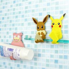 toothpaste, toothbrush holder and pokemon figurines on a tiled wall