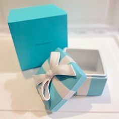 a blue and white box with a bow on the lid sitting on a counter top