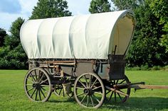 an old covered wagon sitting in the grass