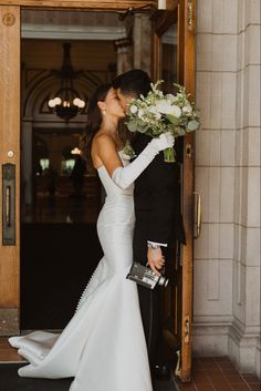 a bride and groom kissing in front of an entrance