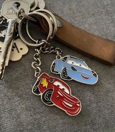 two cars keychains sitting next to each other on top of a leather strap