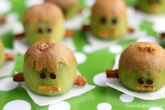 green apples with faces made to look like they are eating something out of the ground