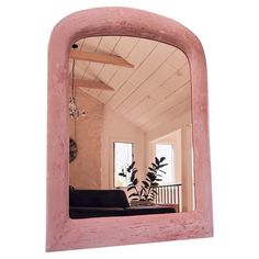 a mirror that is on the wall in front of a couch and table with a potted plant