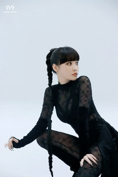 a woman with long black hair sitting on the ground in tights and heels, looking off to the side