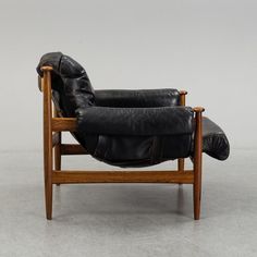 a black leather reclining chair sitting on top of a white floor next to a wooden frame