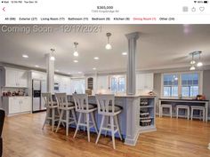 an image of a kitchen with white cabinets and bar stools on the island in the middle