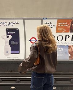 a woman standing in front of a sign with an electronic device on it's back