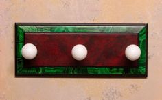 three golf balls mounted to a wall with green and red paint on the bottom half