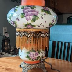 a lamp that is sitting on top of a wooden table with flowers painted on it