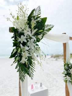 an outdoor ceremony setup with white flowers and greenery on the altar at the beach