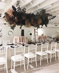 a long table with white chairs is set up for an event or function in the room