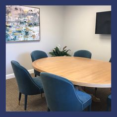 a large wooden table with blue chairs around it in an office meeting room, next to a plant