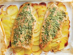 two fish fillets with herbs and potatoes on a baking sheet