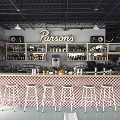 the interior of a restaurant with wooden tables and stools in front of an empty bar