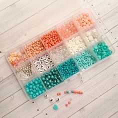 a box filled with lots of different colored beads and bead caps on top of a wooden floor