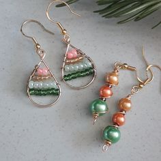 three pairs of earrings sitting on top of a white table next to a pine tree