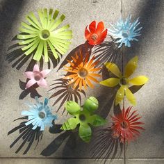 an overhead view of multicolored plastic flowers on the ground with shadows coming from them