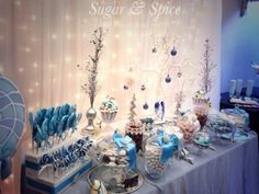 a table topped with lots of desserts and candies next to a window covered in lights