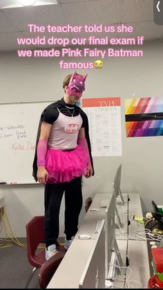 a girl in pink is standing on top of a desk with a batman mask over her face