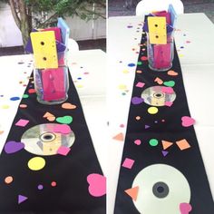 the table is decorated with colorful confetti and cd's in vases