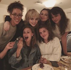 a group of young people posing for a photo at a table with food and drinks