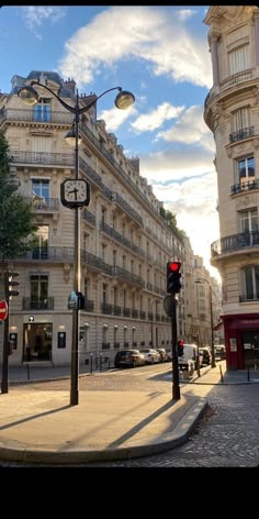 an empty street in the middle of a city with tall buildings on both sides and a red traffic light