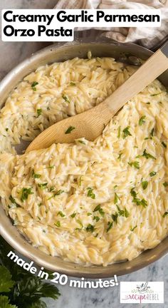 creamy garlic parmesan orzo pasta in a skillet with a wooden spoon