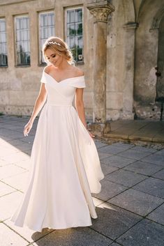 a woman in a white dress is walking down the street with her hand on her hip