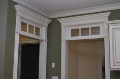 an empty kitchen with green walls and white cabinetry on the door, window sill, and cupboards