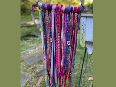 a bunch of colorful ties hanging from a clothes line in the grass next to a trash can