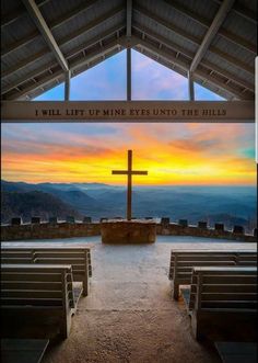 the inside of a church with benches and a cross in front of it at sunset