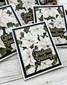 four christmas greeting cards with poinsettis and holly on them, sitting on a table