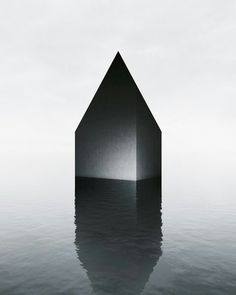 a black and white photo of a house in the water with its reflection on the water