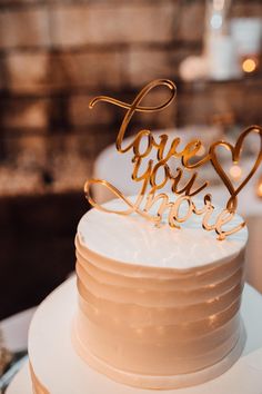 a wedding cake with the word love spelled in gold on top and two tiers