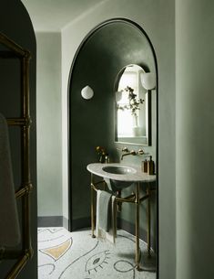 an arched doorway leads to a bathroom with a marble sink and gold faucet