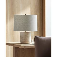 a table lamp sitting on top of a wooden table next to a brown leather chair